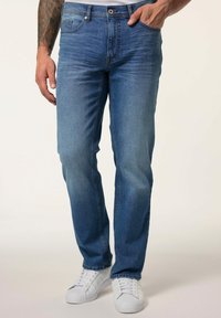 Jeans de mezclilla azul con corte recto, que presentan un sutil desgastado, dos bolsillos frontales y un diseño limpio y clásico, combinados con zapatillas blancas.