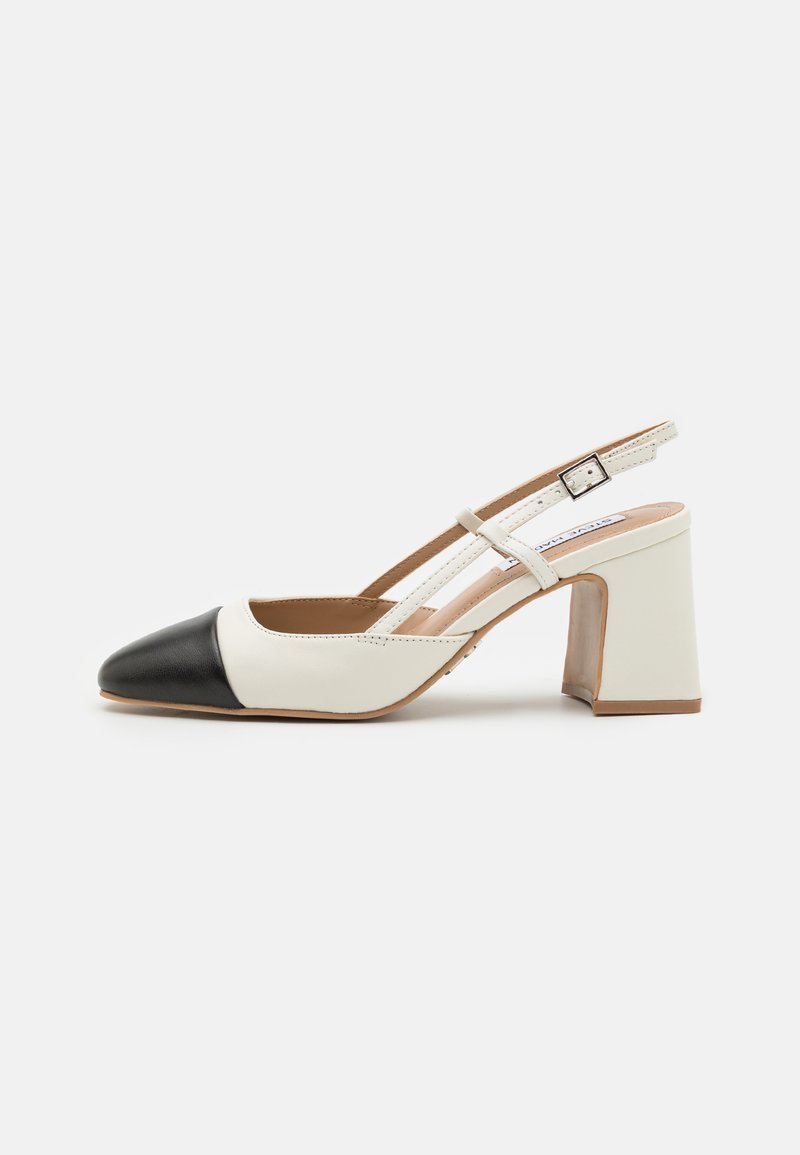 Valkoinen ja musta kaksivärinen slingback-kengät, joissa on lohkare-kenkäkorko, terävä nuppi ja nilkkahihna pienen neliön soljen kanssa.