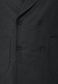 Donkergrijze dubbelbreasted blazer van een textuurstof, met twee platte zakken en zwarte knopen voor sluiting.