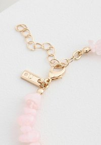 Cierre en tono dorado con un cierre de langosta texturizado, adjunto a una cadena con cuentas de piedra preciosa rosa irregulares en un acabado pulido.