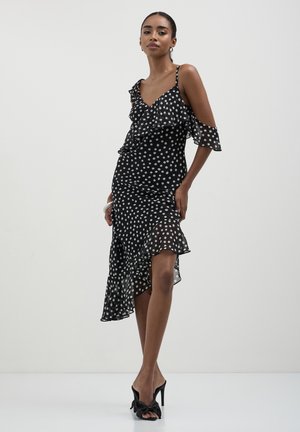Schwarzes Kleid mit Punktemuster, Rüscheneinsatz, asymmetrischem Saum, Schulterdesign mit kaltem Look, leichtem Stoff und taillierter Silhouette.