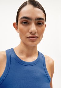 Ribbed blue sleeveless top with a round neckline, displaying smooth texture and fitted design. Background is plain white.