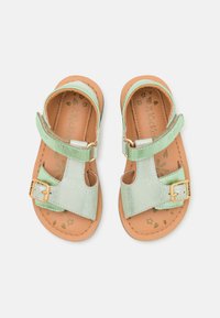 Sandalias de cuero verde con acabado metálico, que cuentan con una correa ajustable con un hebilla dorada y una plantilla color marrón con patrones florales.