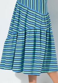 Randig klänning med växlande blå och mintgröna färger samt svarta ränder, lagerdesign och rynkad textur vid sömmarna.