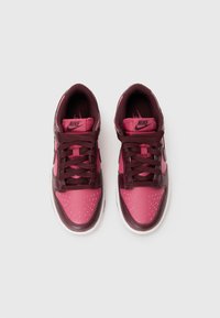 Nike sneakers with a pink and burgundy color scheme, featuring a perforated toe, textured overlays, and thick brown laces.