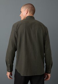 Camicia a quadri con bottoni in verde scuro e blu navy, maniche lunghe, vestibilità rilassata, con spalla posteriore e polsini con un singolo bottone.