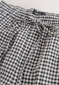 Sort-hvide gingham-mønstrede shorts med elastik i taljen og bindebånd. Blødt stof med løs pasform og plisseret design.