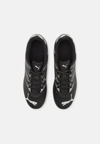 Zapatillas deportivas negras con una parte superior sintética texturizada, detalles en blanco y un logotipo prominente en el costado y en la zona del dedo del pie. Seis ojales para los cordones.