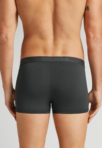 Shorts de sport noirs avec une texture lisse, dotés d'une taille de marque et d'un design ajusté, mettant en valeur la vue arrière et la forme des jambes.