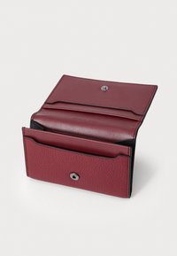 Portafoglio in pelle bordeaux con finitura testurizzata e dettagli neri. Presenta una chiusura a scatto e diverse fessure per carte all'interno.