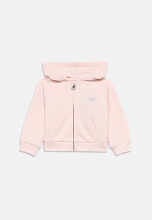 Rosa Kapuzenpullover mit einem Reißverschluss vorne, zwei vorderen Taschen und einer Kapuze. Aus weichem Stoff mit gerippten Bündchen und Saum. Logo auf der linken Brust.