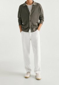 Gray ribbed cardigan with button closure and pockets, paired with loose white pants and beige sneakers. Smooth texture, casual fit.