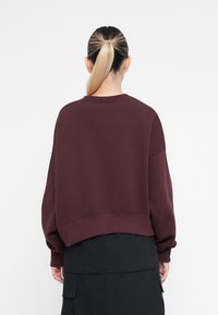 Μαρόν κοντό φούτερ με στρογγυλή λαιμόκοψη και χαμηλώμενους ώμους. Μαλακό ύφασμα, ριμπ μανσέτες και στρίφωμα προσφέρουν δομή και εφαρμογή.