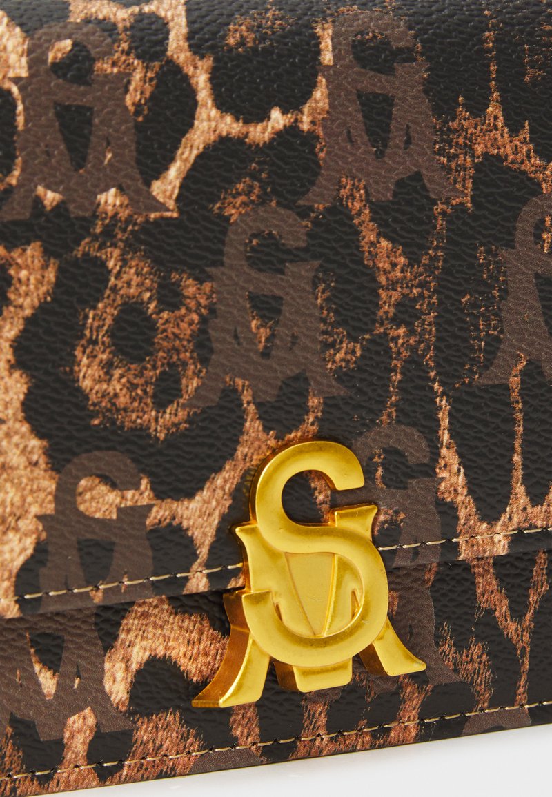 Sac à main en simili cuir avec imprimé léopard, mettant en avant un fermoir logo doré et des détails de couture le long des bords.