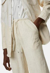 Ljusbeige linneskjorta i kombination med matchande lösa byxor, med elastisk midja och dragsko med metalldelar.