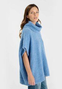 Maglione oversize di colore azzurro chiaro con collo a cascata, realizzato in materiale texturizzato e soffice. Maniche corte, vestibilità ampia e orlo dritto.