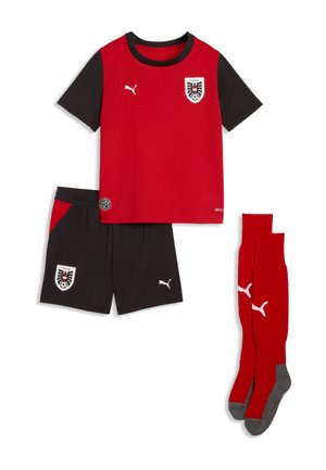 Rotes und schwarzes Fußballtrikot mit kurzen Ärmeln und Logos, schwarze Shorts mit roten Akzenten und passende rote knielange Socken mit grauen Sohlen.