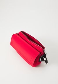 Red rectangular bag made of smooth material, featuring a top zipper closure and black adjustable hardware accents on the side.