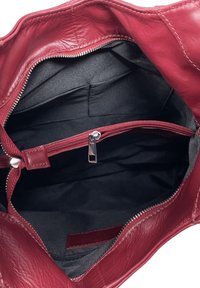Wnętrze głębokiej czerwonej torebki skórzanej z kieszenią na zamek, gładką teksturą i czarną tkaniną wyściełającą. Posiada srebrny detal zamka błyskawicznego oraz dodatkowe przegrody.