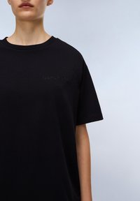 Černé bavlněné tričko s kulatým výstřihem, s vyraženým logem "NAPAPIJRI" na hrudi, krátkými rukávy a volným střihem.