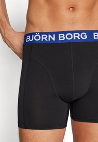 Melni bokseršorti ar zilu elastīgu jostu, uz kuras ir balta uzraksts "BJÖRN BORG". Izgatavoti no gludas auduma ar pieguļošu piegriezumu.