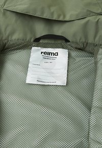 Green, weatherproof jacket interior with mesh lining; features a label indicating size 128/8Y and care instructions.