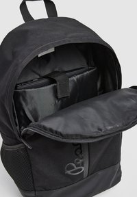 Melnā mugursoma ar ar rāvējslēdzēju, kas izceļas ar gludu tekstūru, iekšējo nodaļu klēpjdatoram ar siksnu un sieta sānu kabatu.