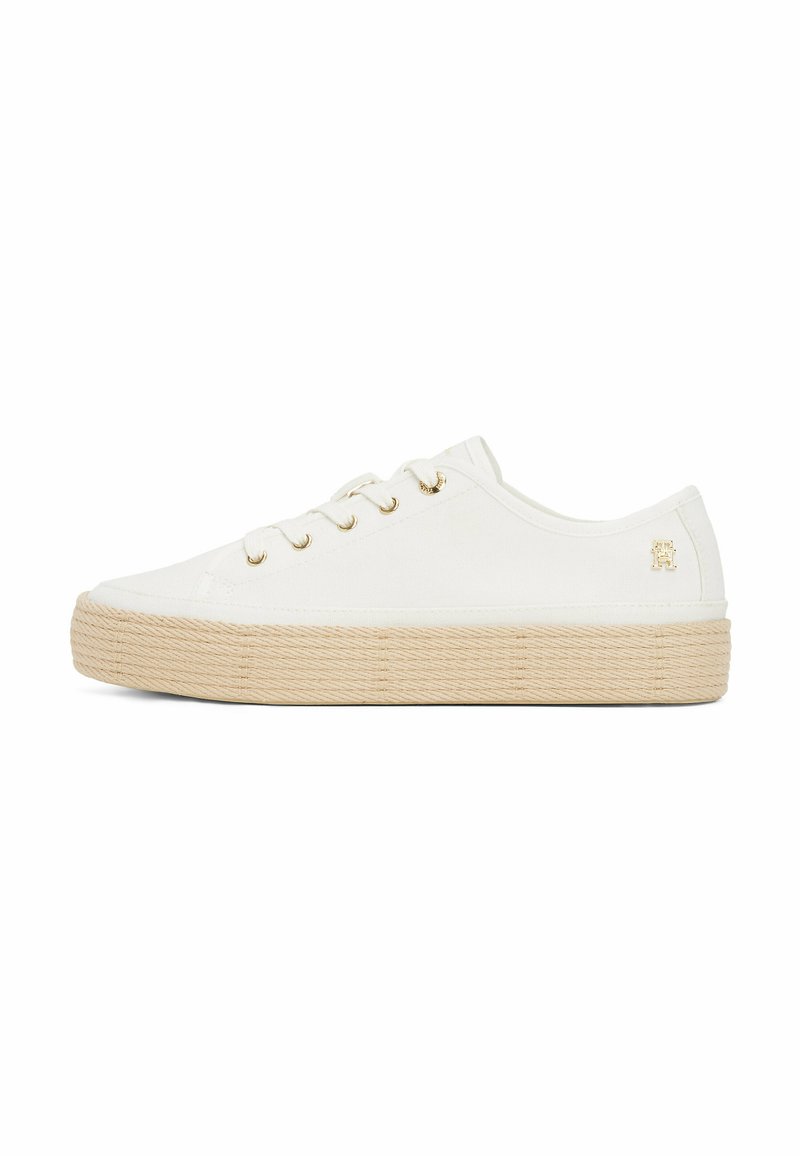 Weiße Leinenschuhe mit beiger, seilähnlicher Sohle, goldenen Ösen und einem kleinen Logo an der Ferse. Niedrig geschnittenes Design mit abgerundeter Zehe.