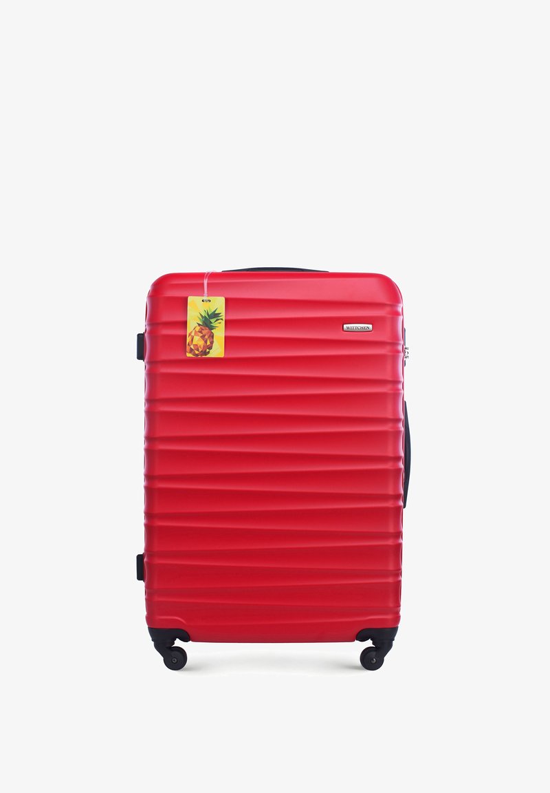 Valise rigide rouge avec un design rainuré, roues noires et une poignée supérieure. Comprend une étiquette de prix sur le thème de l'ananas attachée.