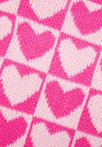 Dzianina w różowo-białą kratę z naprzemiennie ułożonymi serduszkami. Każde serduszko ma intensywny różowy kolor i teksturowany wygląd.