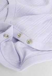 Hele lilla kangas soonilise tekstuuriga, millel on hõbedased trukid krae juures. Pehme materjal hoolikalt õmmeldud detailidega.