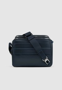 Bolso messenger azul marino hecho de material suave, con cierre de cremallera, correa ajustable y detalles horizontales.