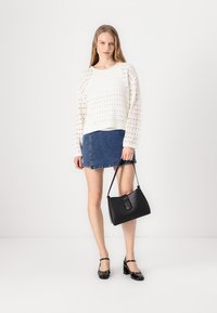 White knitted sweater with textured patterns, denim mini skirt, black handbag, and shiny black strap heels. Displayed in a neutral background.