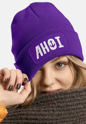 Purple knitted beanie featuring an embroidered "AHOI" patch with an anchor design. The fabric has a ribbed texture and a snug fit.
