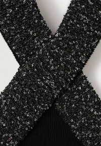 Tela negra texturizada con lentejuelas en un diseño en forma de cruz. Presenta acentos brillantes y una capa inferior suave, lo que enfatiza la profundidad y la dimensión.