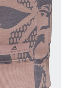 Atletická mikina v jemně růžové barvě s tmavě šedým květinovým vzorem. Obsahuje branding Adidas a Stella McCartney na texturované etiketě.