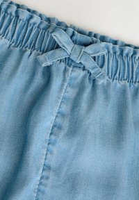 Helle blaue Jeansshorts mit einem rüschengestalteten elastischen Bund und einem Stoffband-Detail. Glatte Textur mit dezenten Nahtakzenten.