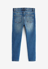 Smala blå denimjeans med en ljus tvätt, utrustade med två bakfickor och en klassisk midja, presenterade med baksidan uppåt.