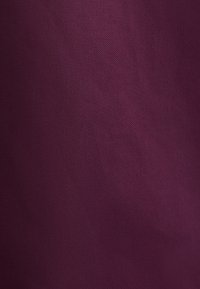 Texture de tissu uni en couleur prune profonde avec un motif de tissage fin et de légères variations d'ombre.