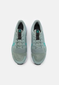 Zapatillas deportivas verde claro con parte superior de malla, acentos en azul verdoso y suelas blancas. Cuentan con una lengüeta acolchada y lazos de encaje negros para mayor soporte.