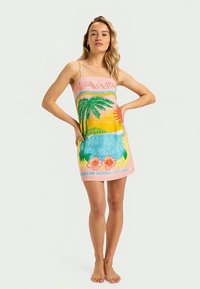 Vaaleanpunainen pyyhemekko, jossa on trooppinen kuvio, mukaan lukien palmut, kukat ja sininen vesi. Spagettiolkaimet, kevyt kangas, rento kesäsuunnittelu.