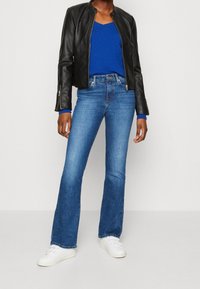 Mustat nahkatakki, sininen pitkähihaisen paita, leveälahkeiset siniset farkut ja valkoiset lenkkarit. Sileä pinta, rento istuvuus ja erottuvat värit.