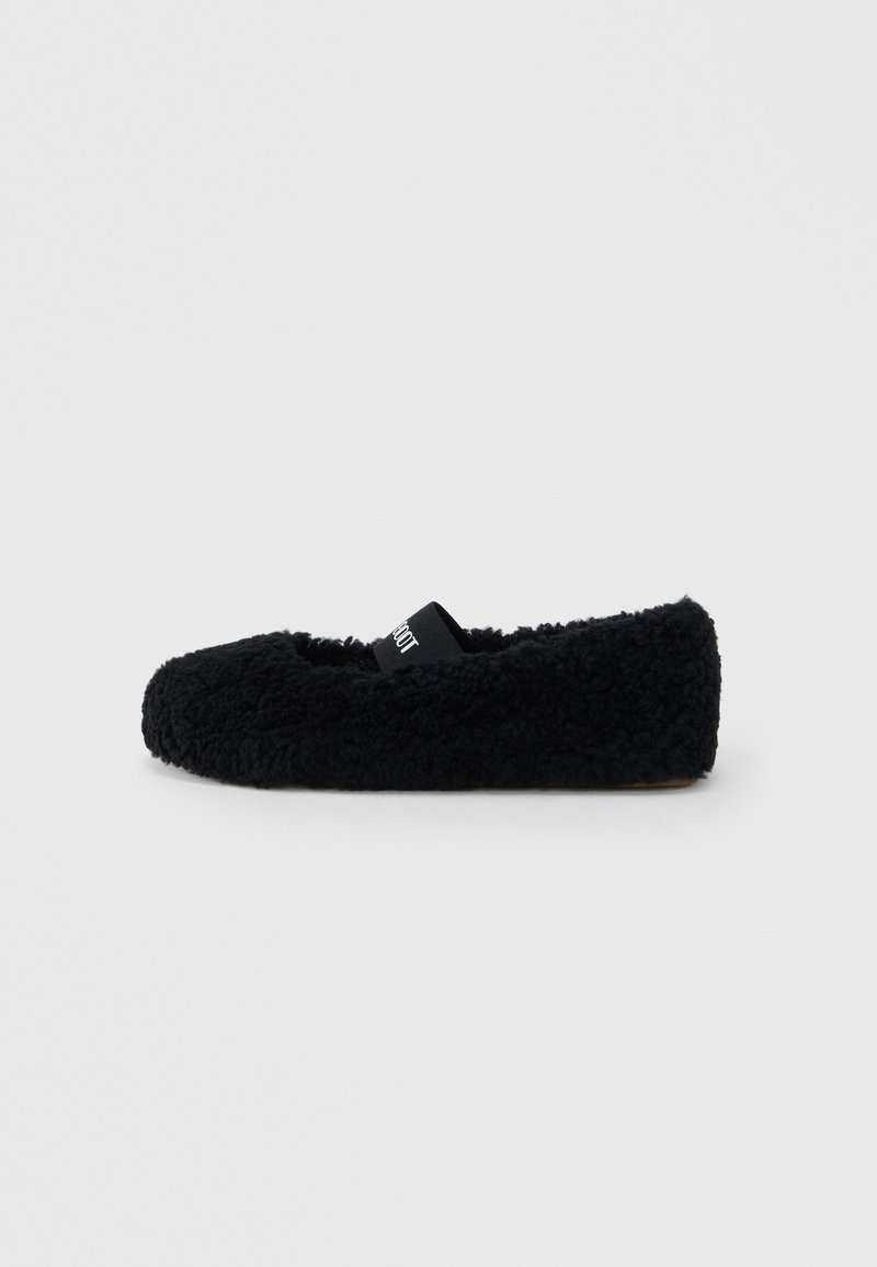 Chaussure noire en tissu pelucheux sans lacets avec une sangle élastique sur le dessus et une semelle plate, présentée sur un fond gris clair uni.