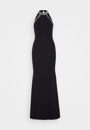 Black gown with a halter neckline, embellished with silver accents. Fitted silhouette, floor-length with a side slit for added detail.