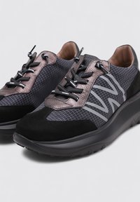 Le scarpe sportive nere e grigie presentano una combinazione di materiali in rete e suede, accenti testurizzati, suole spesse e lacci prominenti.