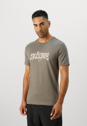 Tricou scurt cu mânecă, de culoare gri închis, cu un logo Nike alb mare, scris într-un font stilizat, centrat pe piept. Material din bumbac neted.