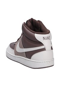 Sneakers alti marroni con accenti bianchi, realizzati con un mix di materiali in pelle e sintetici, con colletto imbottito e suola in gomma. Logo Nike visibile.