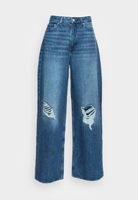 Jeans de perna larga em denim azul médio com detalhes desgastados nos joelhos, apresentando uma cintura alta e um fecho de botão e zipper.