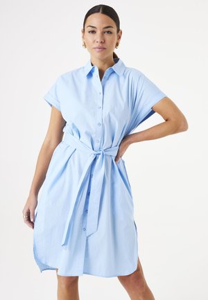 Vestido de camisa azul claro hecho de algodón, con frente abotonado, mangas cortas enrolladas y un detalle en la cintura atado para un ajuste ceñido.