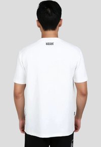 Hvid bomulds T-shirt med korte ærmer, med et lille "WRONG FRIENDS" logo på bagsiden af halsudskæringen og en afslappet pasform.